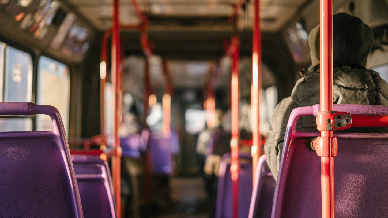 back-of-bus-looking-at-purple-bus-seats-and-bronze-poles