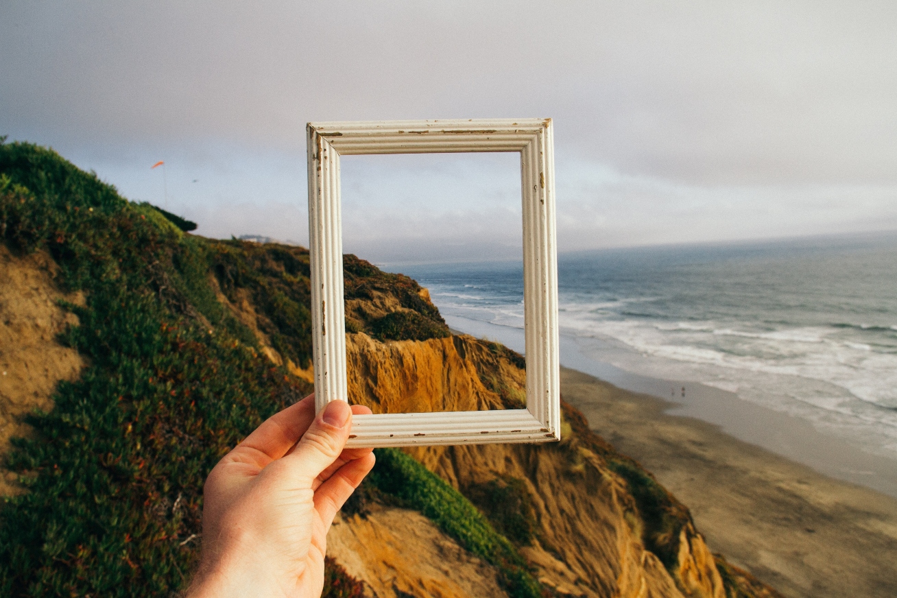 Person-holding-frame-overlooking-cliff-side