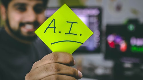 Person holding green sticky note with AI written on it.
