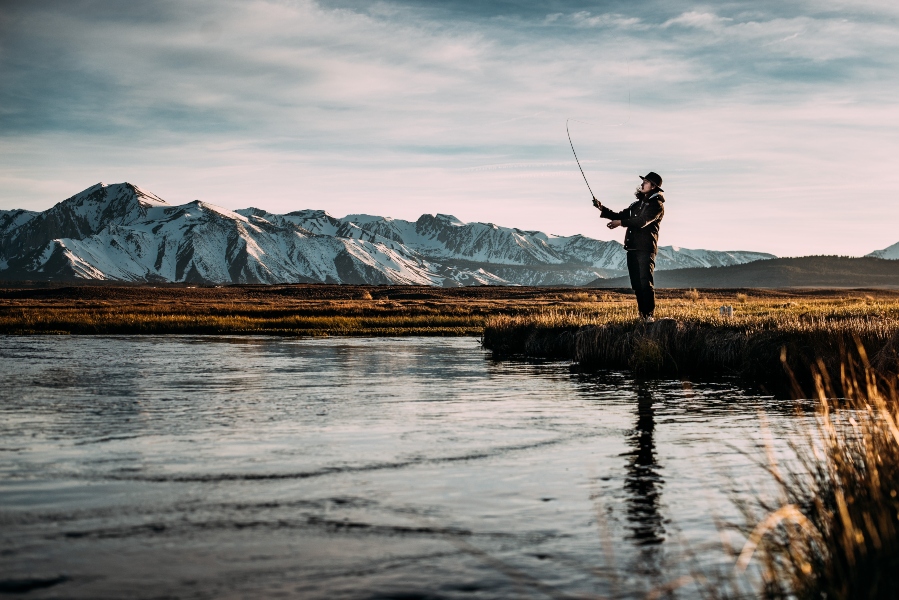 man-fly-fishing-mountains-in-background