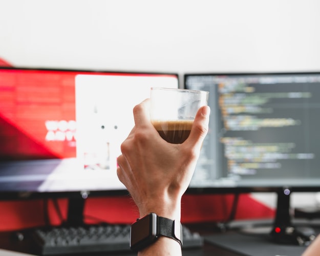 Hand with coffee cup at computer