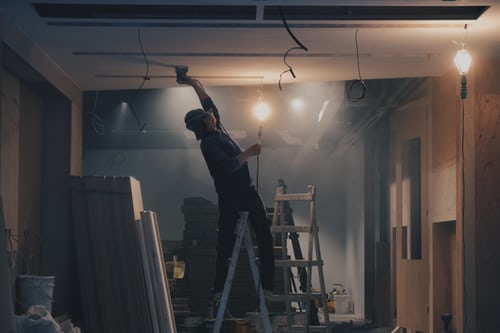 Man painting ceiling in building