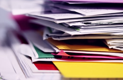 Files stacked messily on a desk