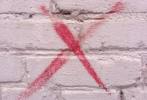 Red X spray painted on white wall