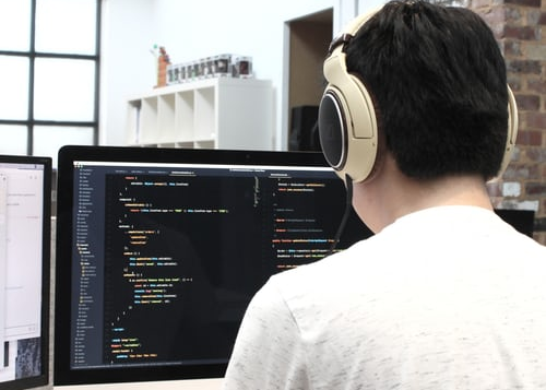 Person with headphones coding at monitor with 
