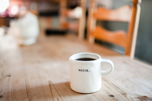 Coffee mug on table that says begin