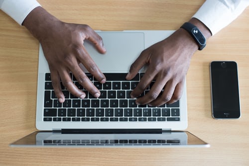 Man typing on macbook on table