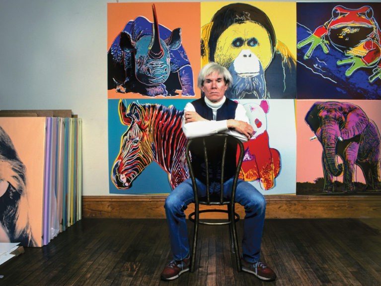 Andy Warhol in front of his artwork