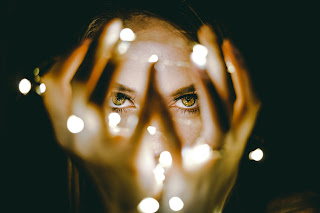 Person looking through open fingers to lights